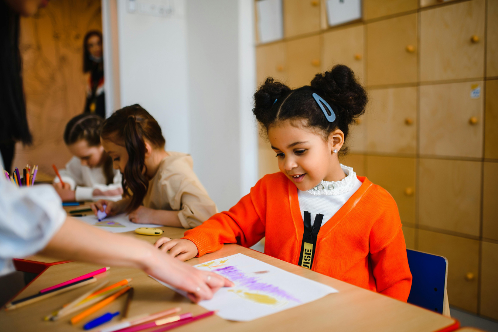 Young learners seated at a table working on colouring pictures
