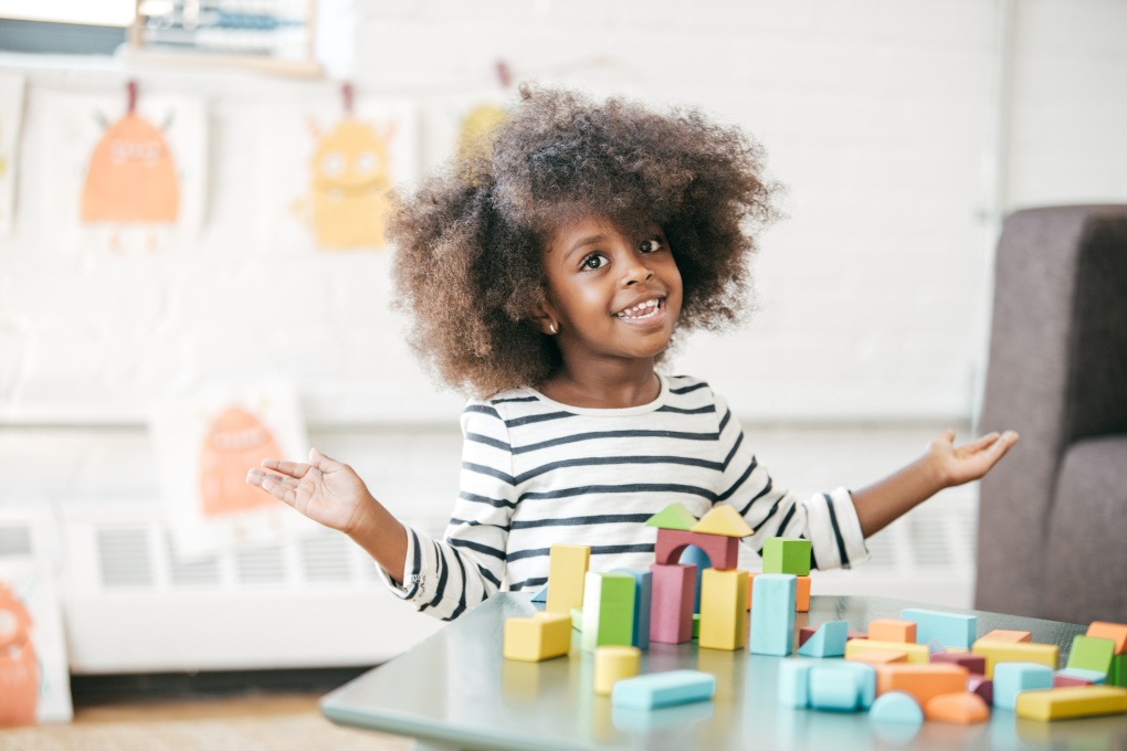 Smiling child playing with colourful blocks — perfect for quiet time, creative play, or reinforcing learning themes like animals and shapes.